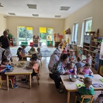 Dzieci siedzą przy stolikach i kroją owoce