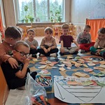 Grupa dzieci siedzi z obrazkami owoców i warzyw