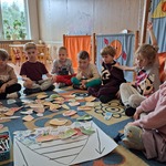 Grupa dzieci siedzi z obrazkami owoców i warzyw