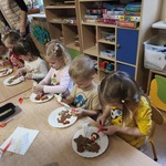 Dzieci siedzą i dekorują pierniczki