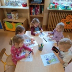 Dzieci pracują przy stoliku z kartą zadań
