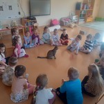 Dzieci siedzą w kręgu dookoła kota